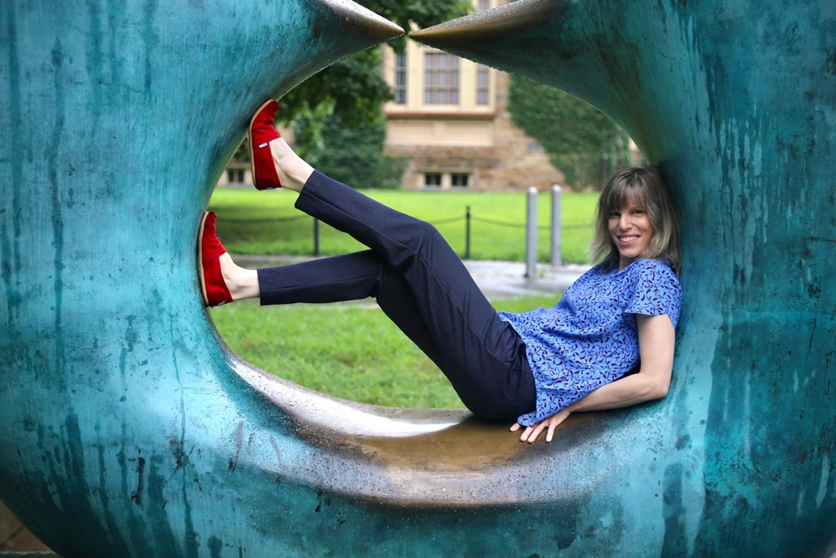 Jessica McKay laying in a large circular sculpture in a park